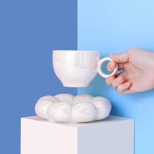 Pearlescent white sunflower ceramic coffee cup and cloud saucer set held in hand