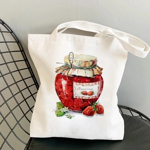 White canvas tote bag featuring strawberry jam watercolor print on a black metal chair