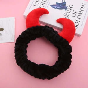 Détail de cornes de diable rouges sur un bandeau noir en peluche sur fond rose esthétique