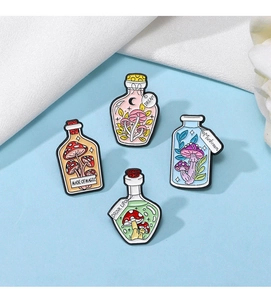 Detail of four mushroom enamel pins in magic bottles on white silk and blue background