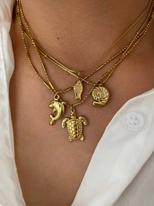 Detail of layered gold titanium necklace with sea turtle, dolphin and shell pendants