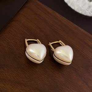 Gros plan de boucles d'oreilles perles en cœur avec anneaux dorés sur table en bois