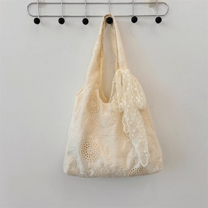 Detailed view of cream lace tote bag featuring hollow floral embroidery and ribbon bows