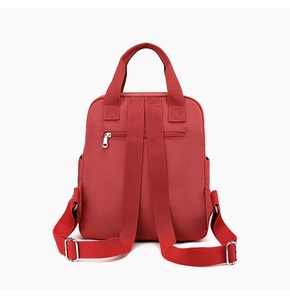 Detail of red nylon backpack back side with adjustable straps and zippered safety pocket