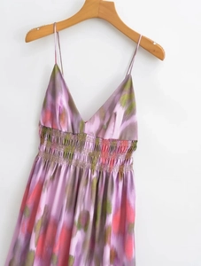 Detail of purple floral tie-dye satin dress with thin straps and waist pleats on a hanger