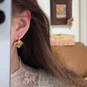 Boucles d'oreilles losanges vintage dorées avec diamants portées par un mannequin