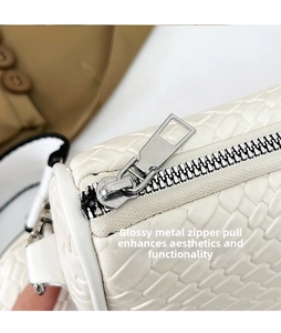 Close-up of silver metal zipper puller on white woven texture crossbody bag detail