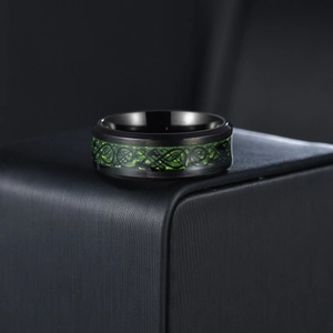 Macro detail of men's titanium steel ring featuring a green Celtic dragon inlay on black band