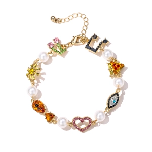Gold plated beaded bracelet with colorful charms like evil eye, heart and cactus on white
