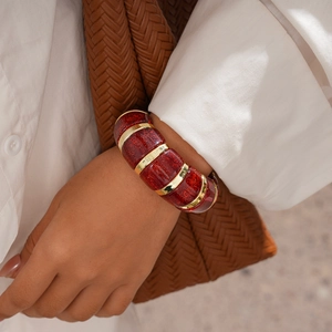 Detail of red glitter acrylic bangle with gold accents on wrist with cotton shirt