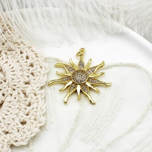 Detail shot of a golden sun pendant with micro-inlaid crystals on elegant lace