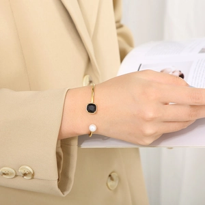 Elegant gold C-shaped stainless steel cuff with square black stone and white pearl detail