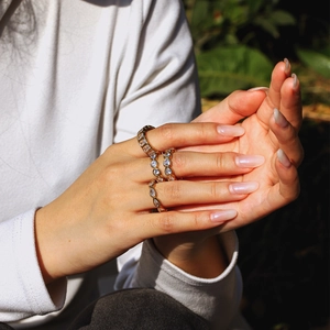 Close-up of stacked gold heart and marquise cut zircon rings worn on a model hand