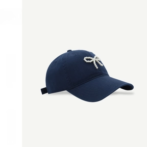 Detail of navy blue cotton baseball cap with hand-sewn pearl bow decoration