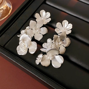 Vue détaillée de boucles d'oreilles fleurs argentées avec glands sur un plateau noir