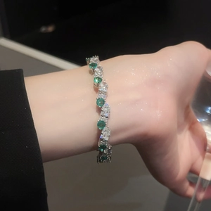 Detail of a sparkling tennis bracelet with green and white zircons on a silver base