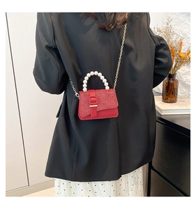 Detail of red glitter crossbody bag with elegant pearl handle and gold chain strap