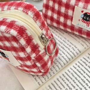 Macro shot of red and white plaid plush fabric storage bags on an open book