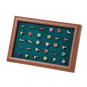Walnut wood jewelry tray with green velvet lining displaying assorted gemstone rings
