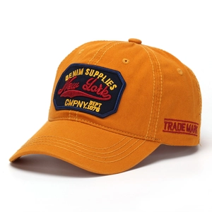 Detail of New York embroidery on mustard yellow cotton twill baseball cap with side stitching