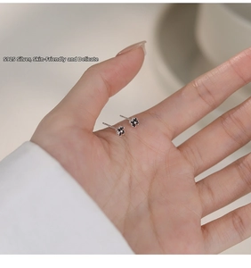 Detailed view of S925 sterling silver black clover stud earrings on hand