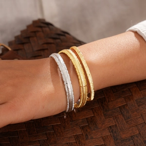 Detail of stacked 18k gold and silver plated geometric bangles with fine textured design