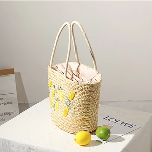 Large straw tote bag with lemon embroidery and beige drawstring liner for beach vacations
