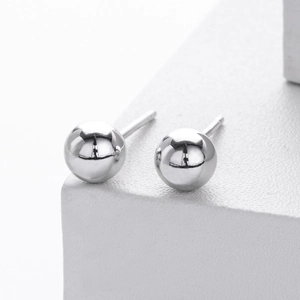 Macro detail of polished S925 sterling silver ball stud earrings on white pedestal