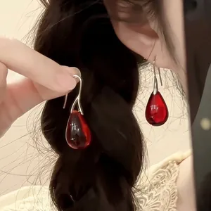 Macro shot of red teardrop crystal earrings with silver hooks on model detail