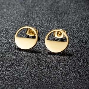 Macro view of minimalist golden stainless steel geometric round earrings on black display
