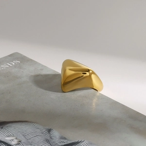 Details eines klobigen goldenen Titanstahlrings mit geometrischem Design auf Buchkante