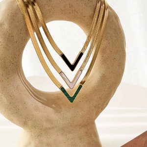 Detailed close-up of gold V-shaped pendants with malachite, shell, and black inlays