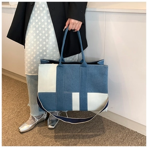 Detailed close-up of a blue denim and white canvas patchwork tote bag with strap