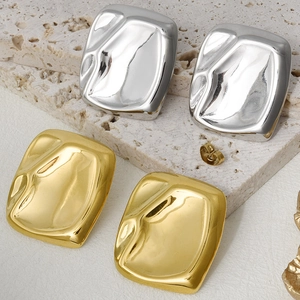 Macro shot of polished 18k gold and silver irregular liquid metal square stud earrings
