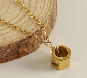 Detail of gold-plated hexagonal nut pendant with small inset crystal on delicate chain