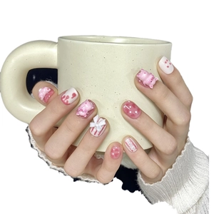 Cute pink and white press-on nails with 3D pig and bow charms on short round nails