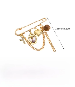 Detail view of gold vintage safety pin brooch with cross, heart, and religious medal