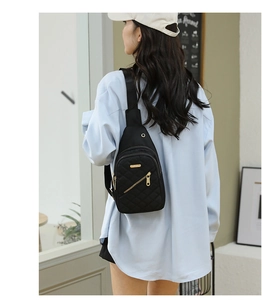 Rear view of a model wearing a black quilted nylon chest bag with adjustable strap