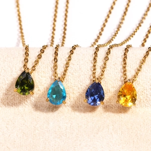 Gold necklaces featuring colorful teardrop zircon birthstone pendants on beige display