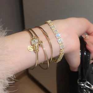 Détail du bracelet tennis doré et des joncs superposés orné de pierres en zircon brillant