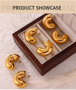 Detailed macro view of 18K gold plated C-shaped chunky earrings on a wooden jewelry box