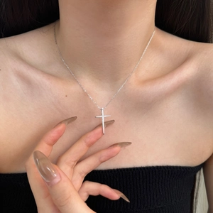 Detail of silver cross pendant necklace with micro-pave stones on female model