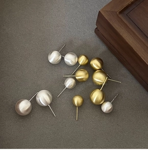 Macro detail of brushed matte ball stud earrings in gold and silver finish