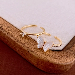 Detail of vintage gold butterfly ring with zircon and white shell on a wooden stand