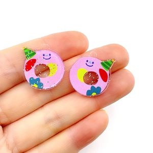 Detailed view of pink acrylic donut alphabet charms with glitter finish held in hand
