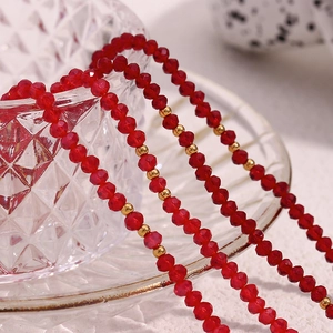 Macro shot of red faceted crystal beads and gold spacer beads on a textured glass