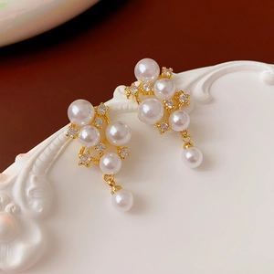 Detail of vintage gold-plated earrings with pearls and shimmering cubic zirconia stones