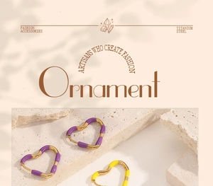 Macro detail of gold-plated titanium heart earrings with purple and yellow enamel coating