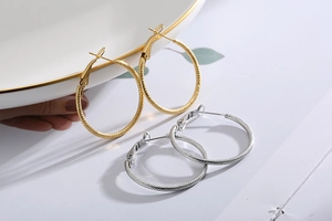Detailed macro view of gold and silver twisted rope texture hoop earrings on white porcelain