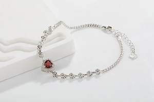 Macro shot of heart-shaped red gemstone bracelet with silver accents and adjustable chain